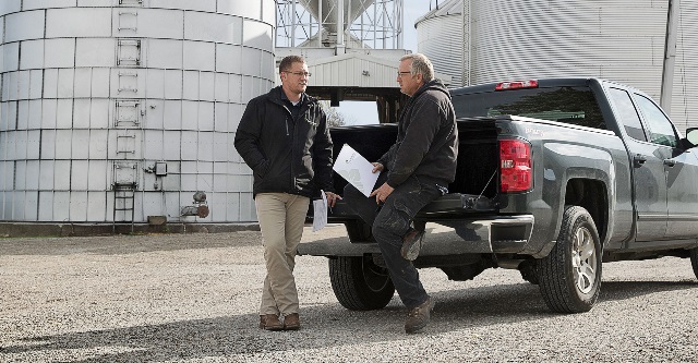 Two men talking on truck tailgate.