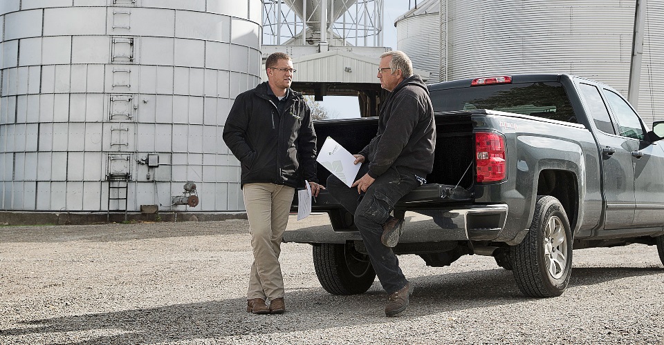 Two men talking on truck tailgate.