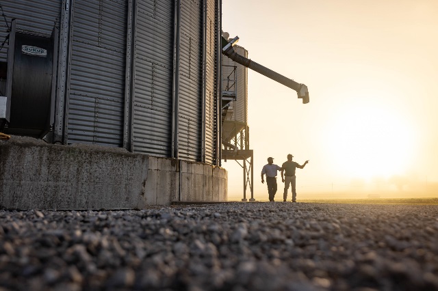 Farm Credit Mid-America crop insurance agent walks with customer by grain bin