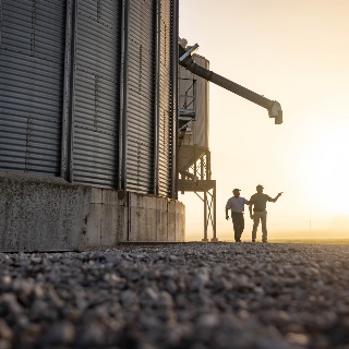 Farm Credit Mid-America crop insurance agent walks with customer by grain bin
