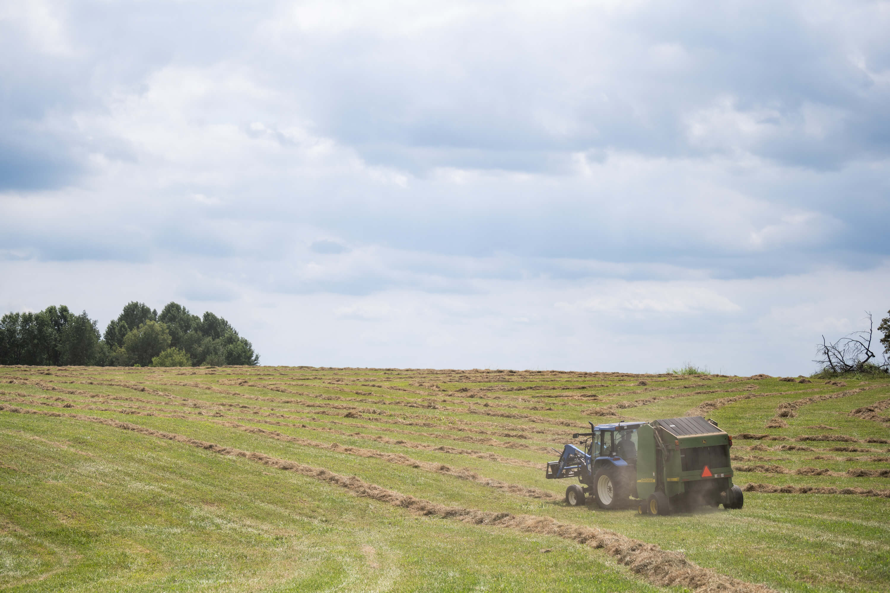 Tractor and baler in hay field representing farmland financing and agricultural loan planning