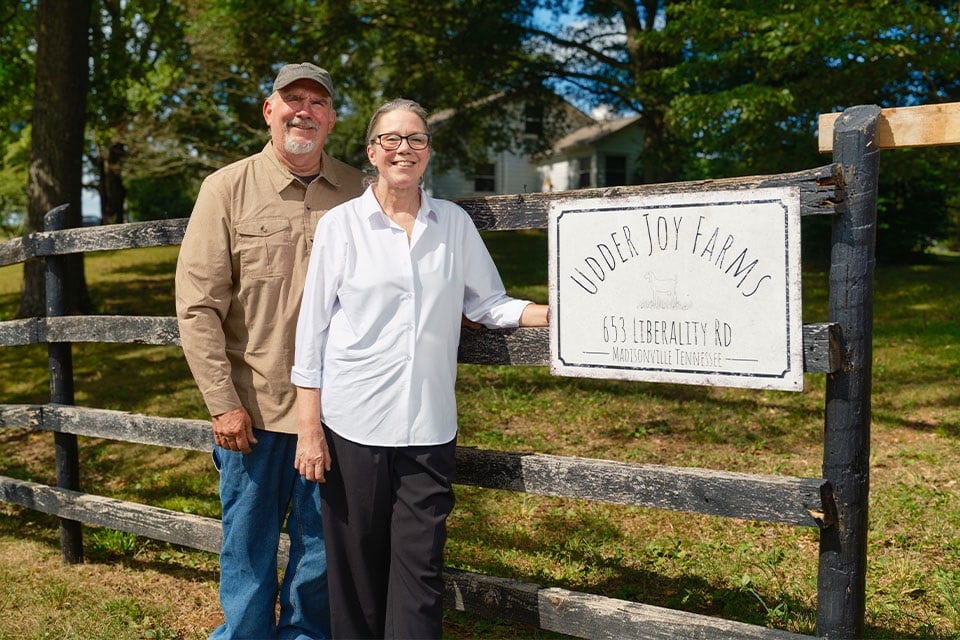 Rural 1st customers Suzanne and Doug Harper stand in front their farm's sign.