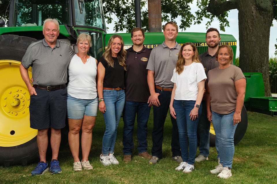 Poppin' Cobs team of farmers and business owners stand in front of a tractor next to field financed by Farm Credit Mid-America.