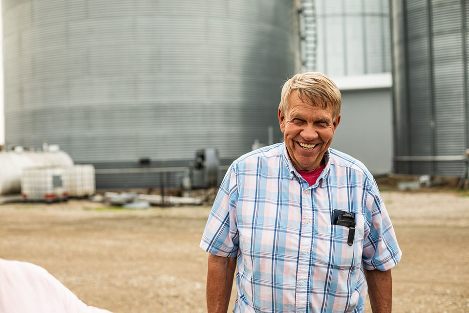 Customer stands outside of grain bins financed through Farm Credit Mid-America.