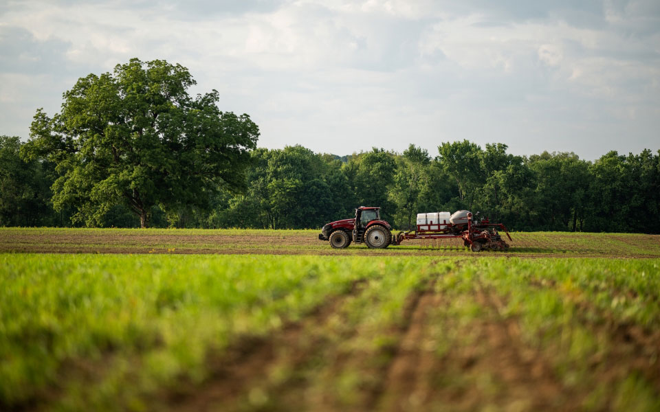 Tractor pulls planter across farm land financed by Farm Credit Mid-America.