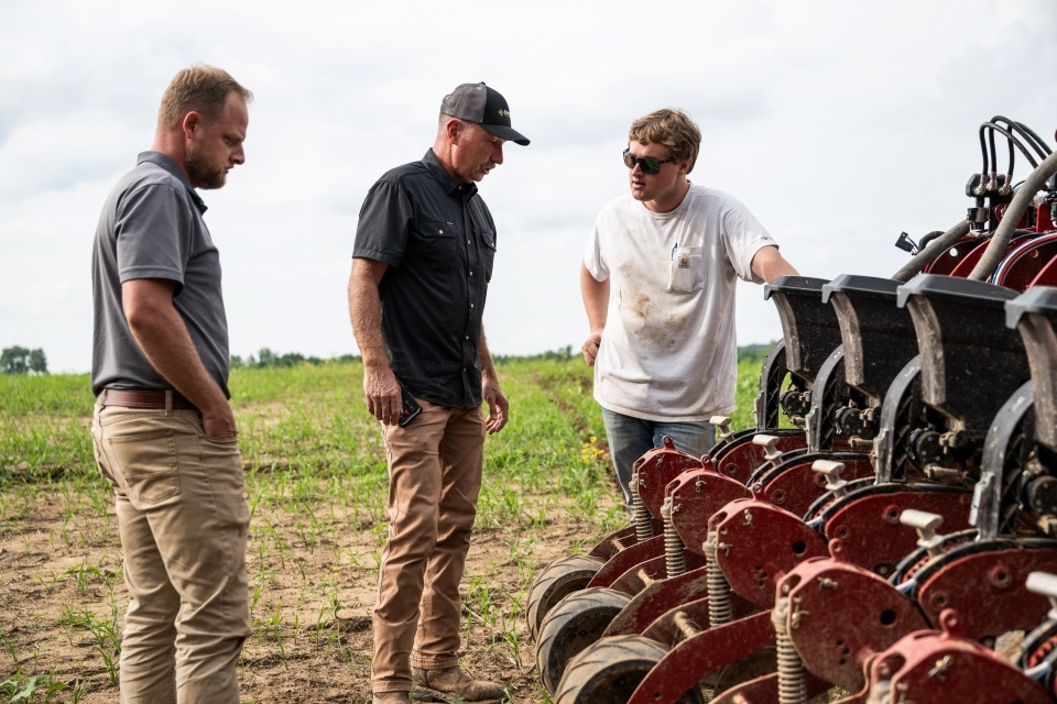 Old and young generation farmers troubleshoot a planter