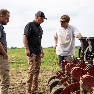 Old and young generation farmers troubleshoot a planter