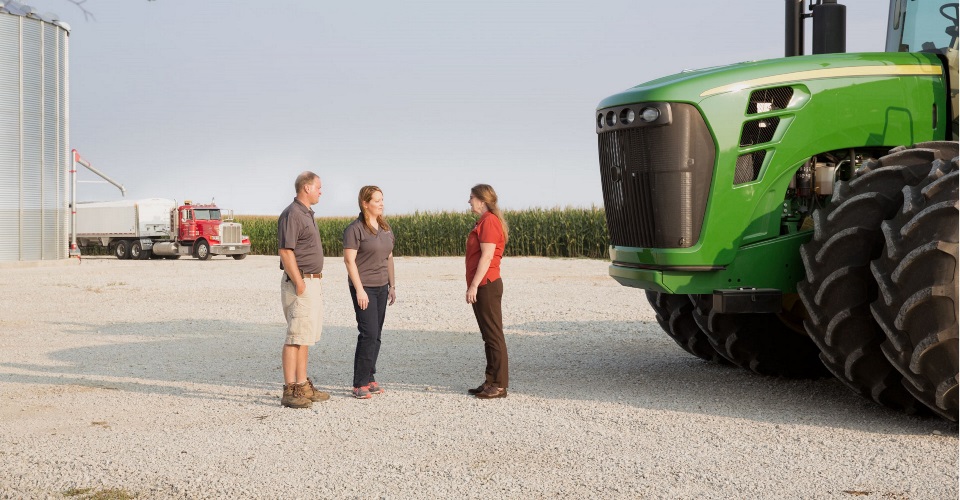 People talking next to tractor.