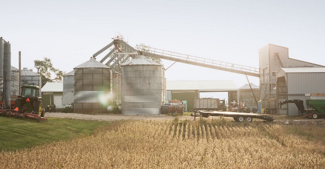 Farm landscape of grain bins and soybean field.