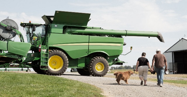 Green combine and two people walking.