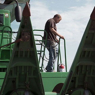 Man stepping out of a combine purchased with an equipment loan from Farm Credit Mid-America.