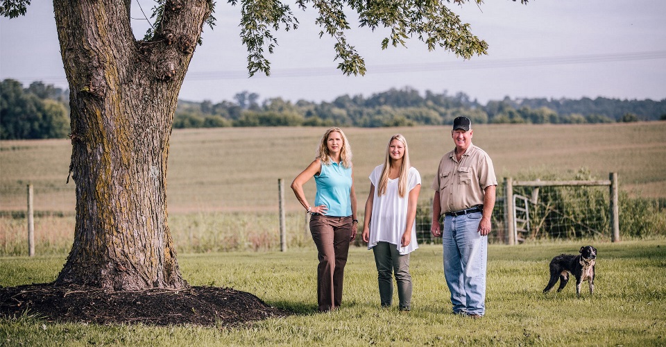 Three people standing under a tree.