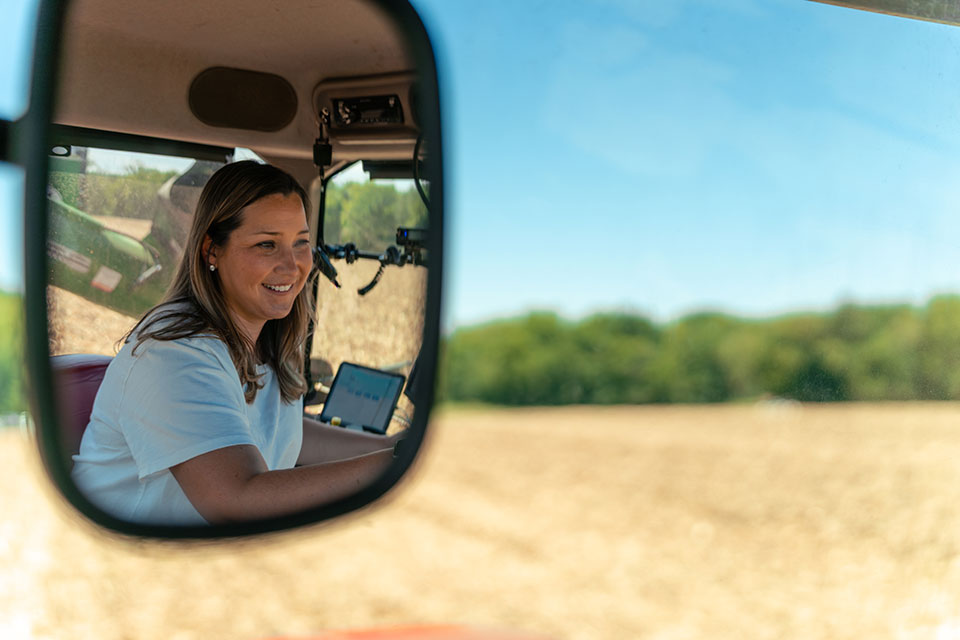 Hutchinson-167-opt View of a woman reflected in a side-view mirror while driving a farm vehicle.