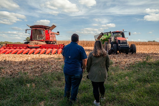 A couple stands gazing at their farm machinery.