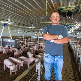 Hog farmer stands in barn financed by Farm Credit Mid-America