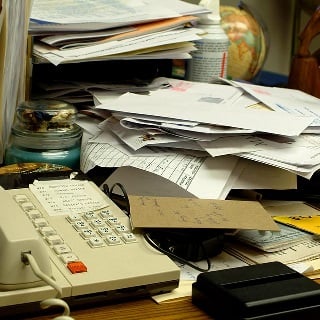 An office desk littered with papers and a landline phone