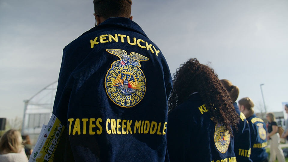 A line of students wear FFA jackets with Tates Creek Middle printed on the back of them.