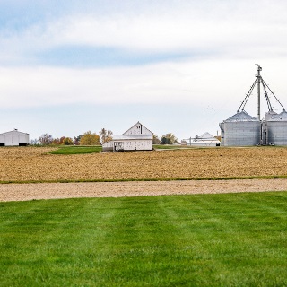 Farm landscape with white barn and metal grain bins.