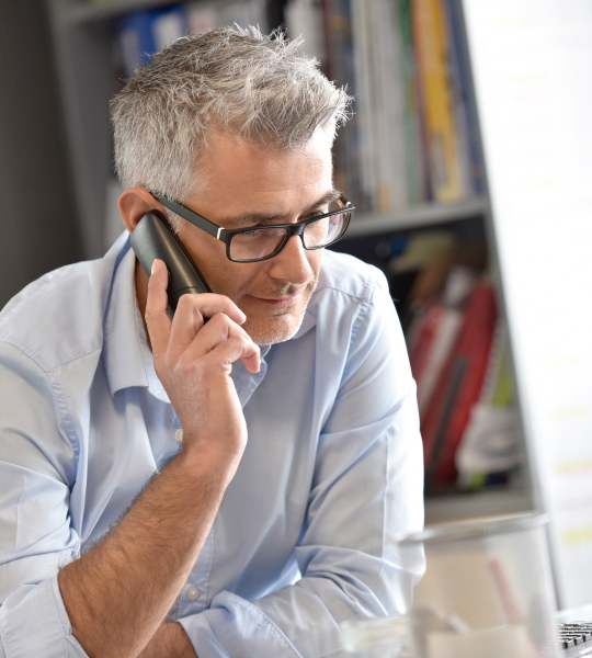 Man talks on a phone at a desk.