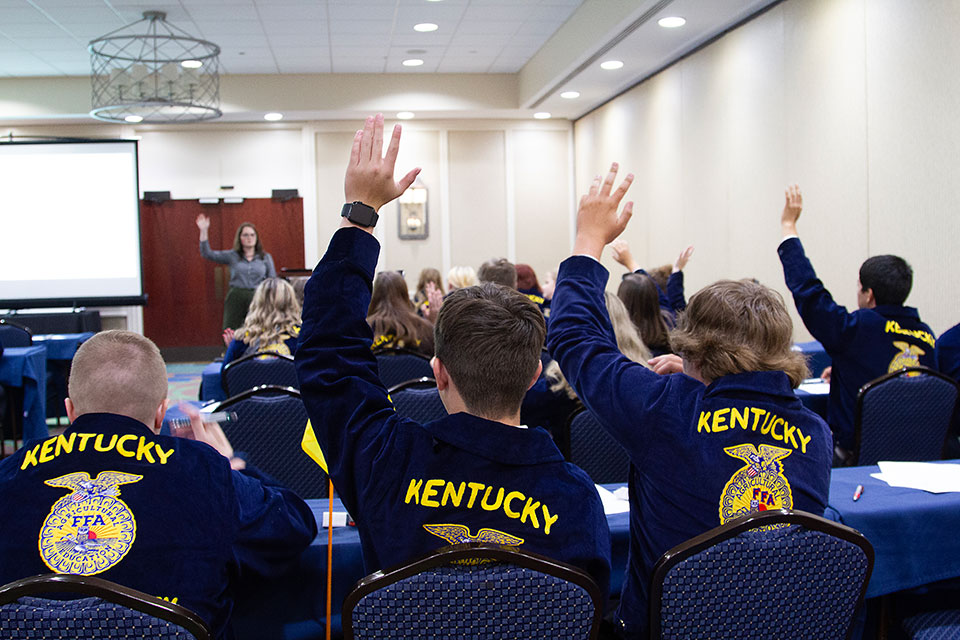 Young farmers raise their hands at a FFA meeting