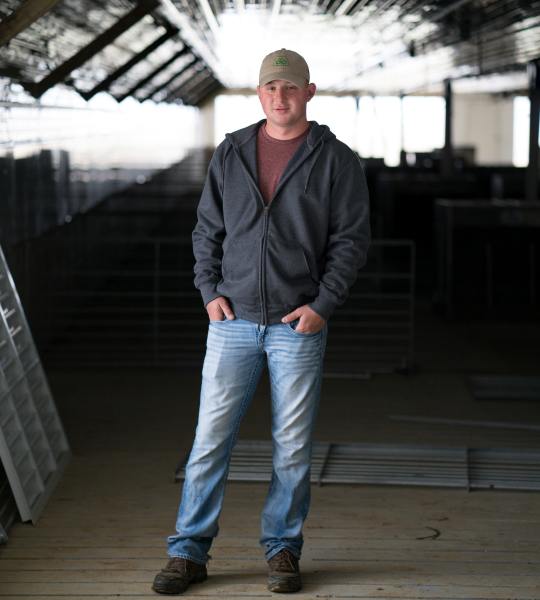 Farmer standing in a metal building.