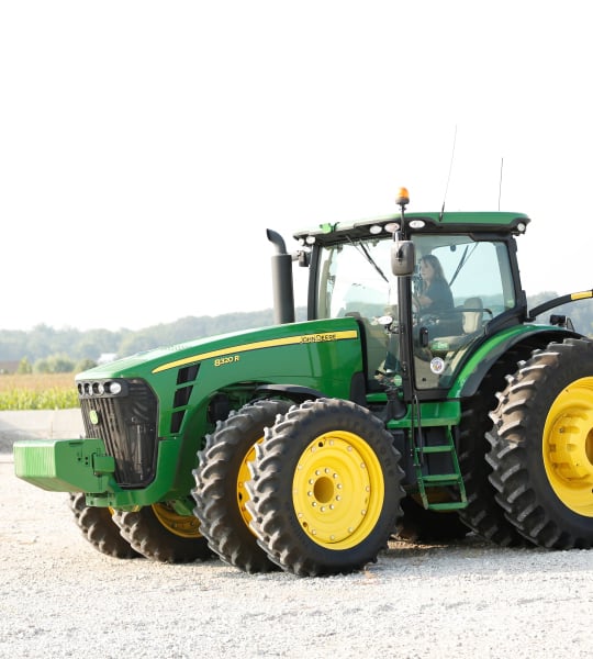 Woman driving large green tractor.