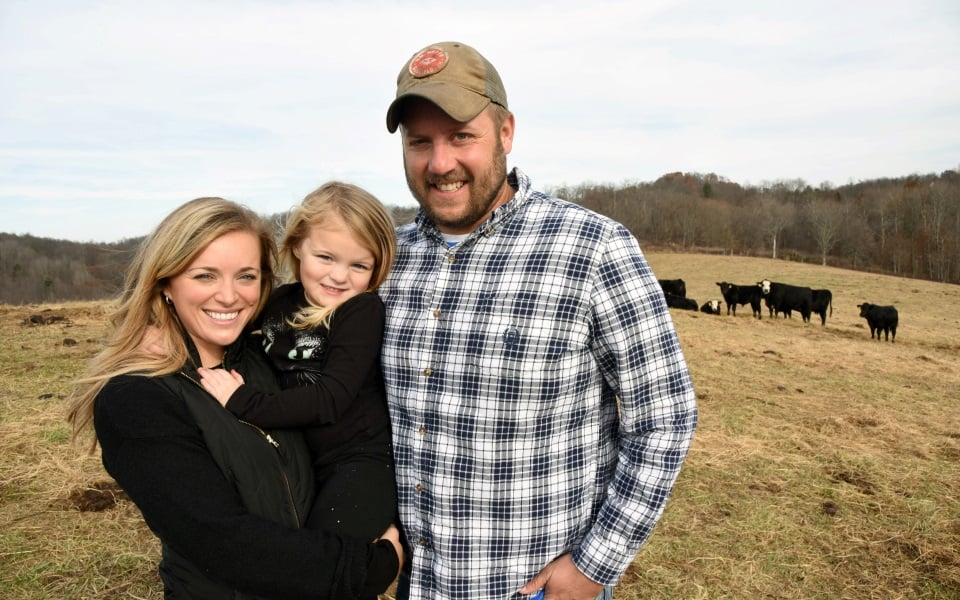 Family stands in a cattle field.