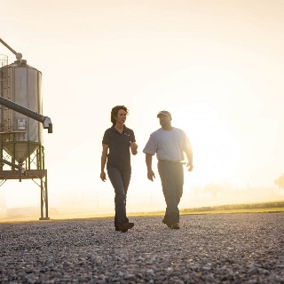 Two people walking by grain bins.