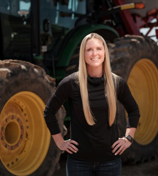 Woman standing in front of a large green tractor.