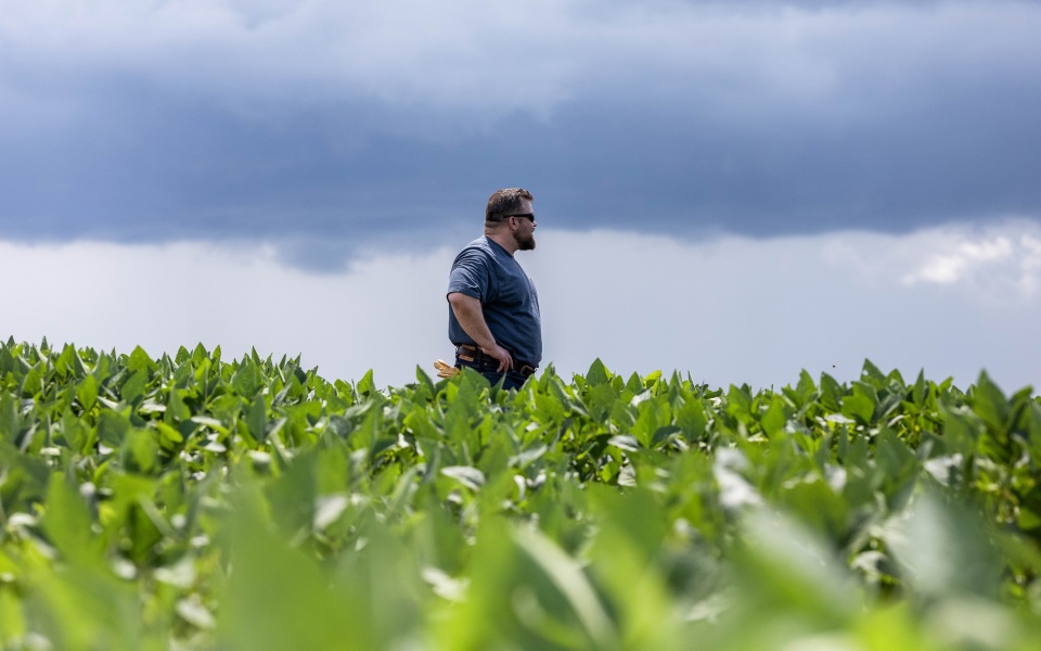 Farmer stands in field as storm rolls in