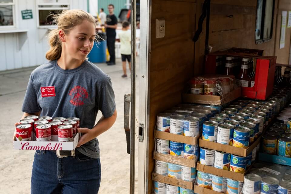 Young woman places donated food in trailer