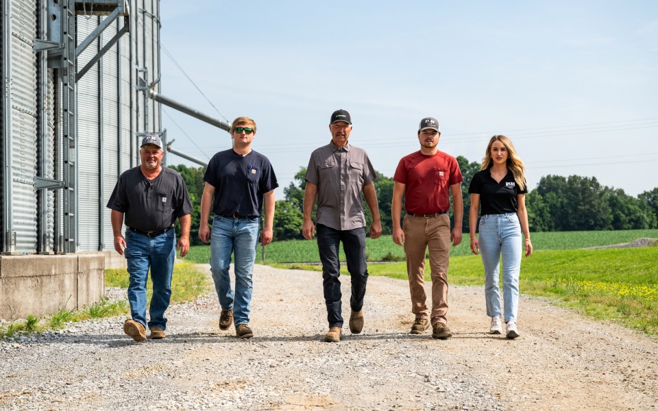 Multigenerational farmers walking by grain bins