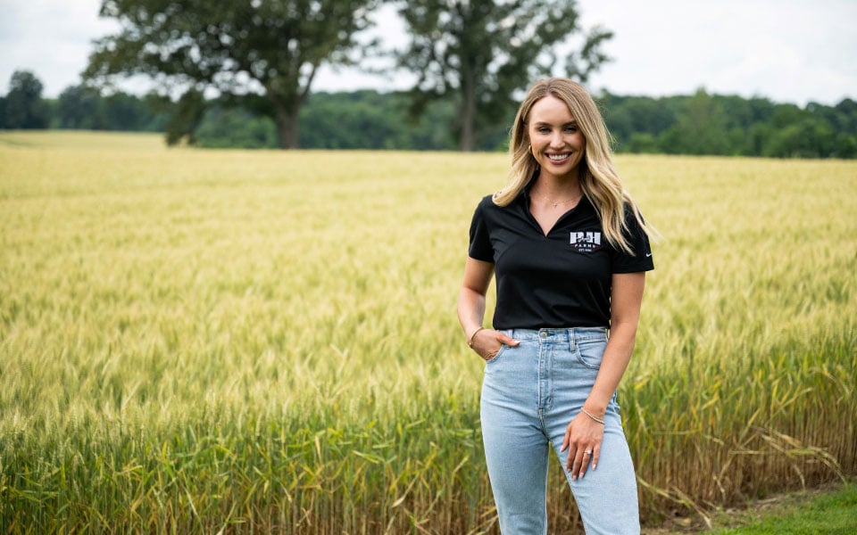 Cali Parish stands in front of wheat that is grown on farm real estate financed by Farm Credit Mid-America.
