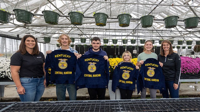 Members of the Central Hardin, Kentucky chapter of FFA hold up their jackets with the FFA emblem on them.
