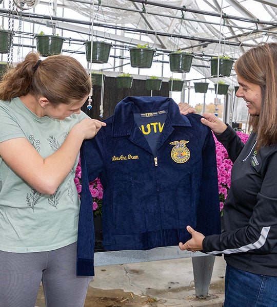 A young woman is presented with an FFA jacket with her name on it.