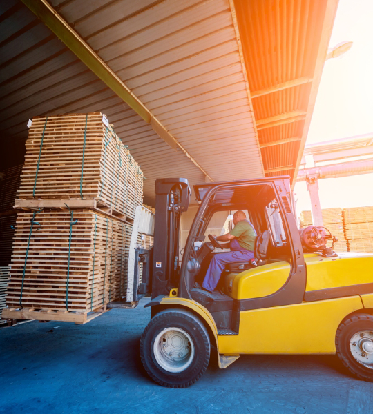 Forklift moves pallets of wood.