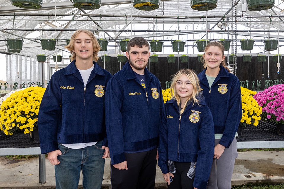 Members of FFA pose in front of flowers.