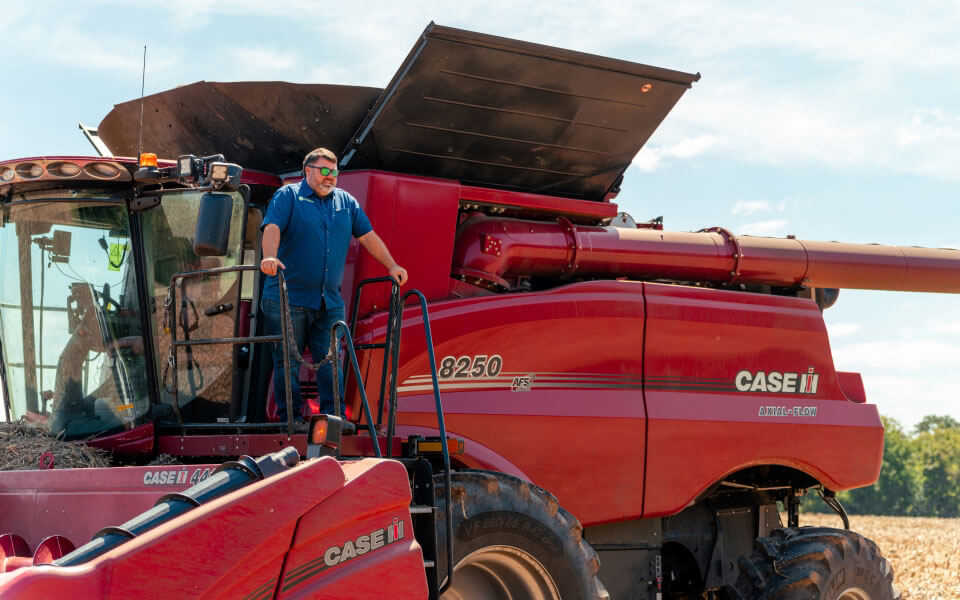 Farmer standing on combine financed through farm equipment loan solutions