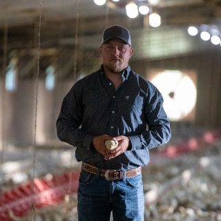 Poultry grower stands in barn financed by Farm Credit Mid-America