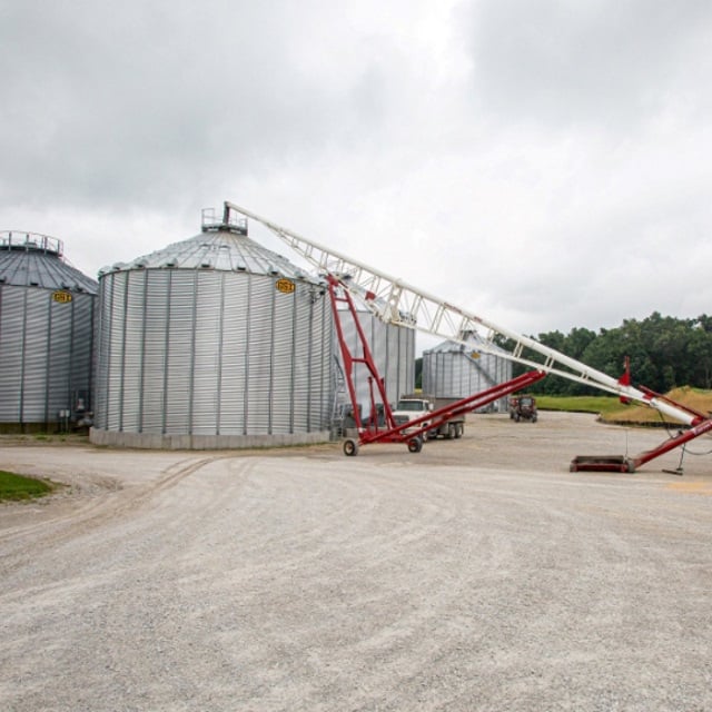 Grain bins with a red auger.