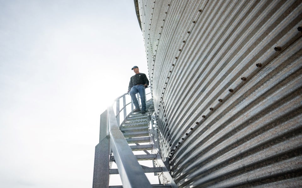 Man walks down a grain bin staircase.