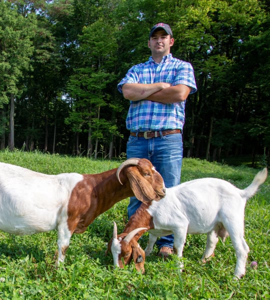 Farmer standing with two goats.