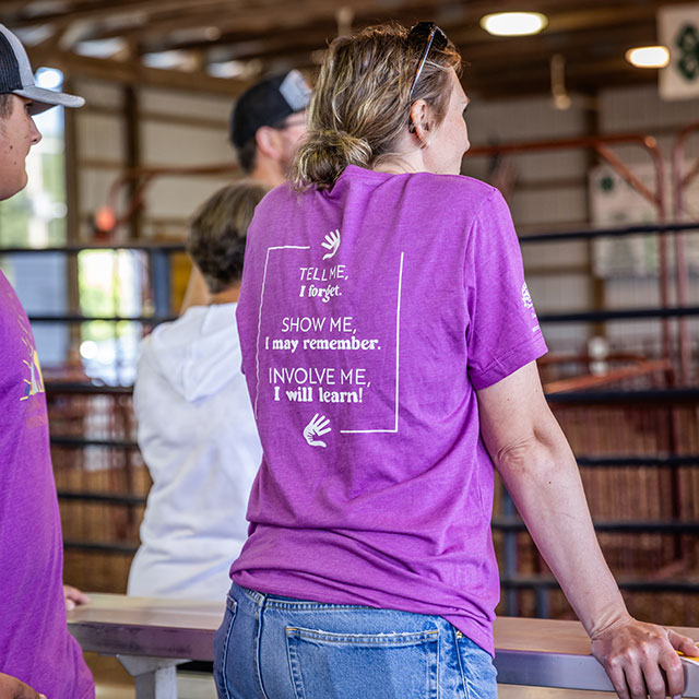 The back of a t-shirt reads, Tell me, I forget. Show me, I may remember. Involve me, I will learn!