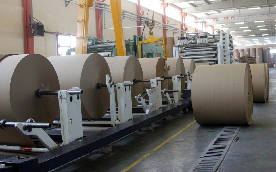 Large rolls of brown paper on a manfacturing line.