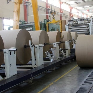Large rolls of brown paper on a manfacturing line.