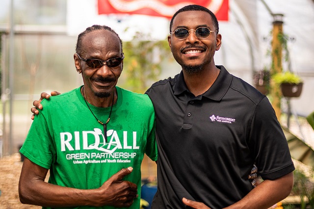 A man with a Rid-All Green Partnership t-shirt poses with a man in a Farm Credit Mid-America polo shirt.