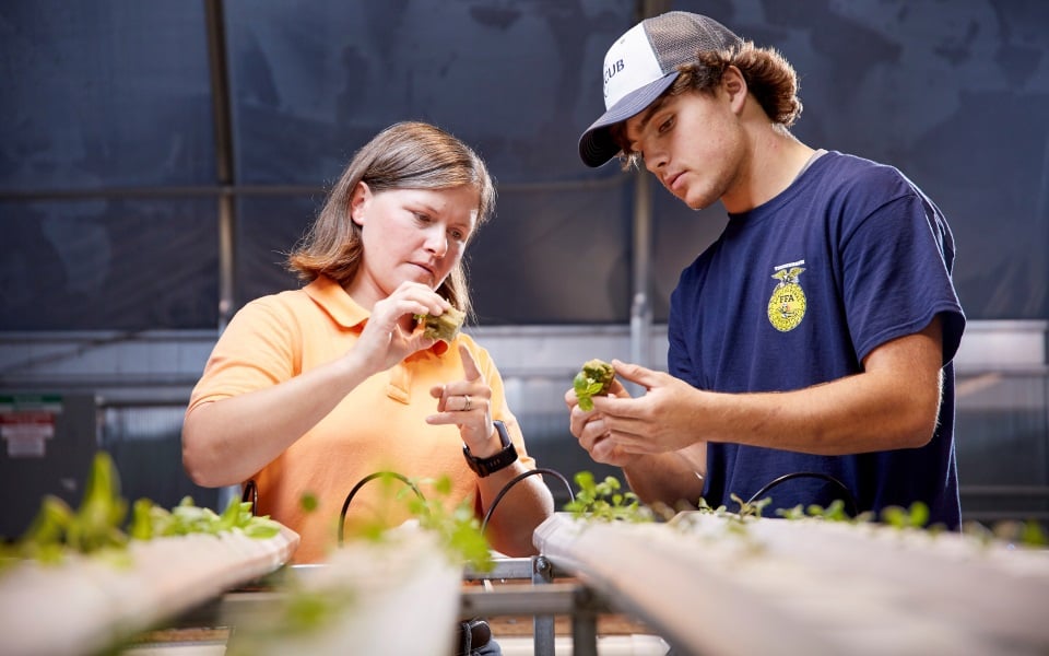 Teacher and high school student in greenhouse.