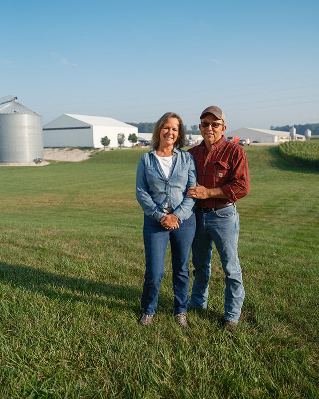 Man and woman stand in front of farm