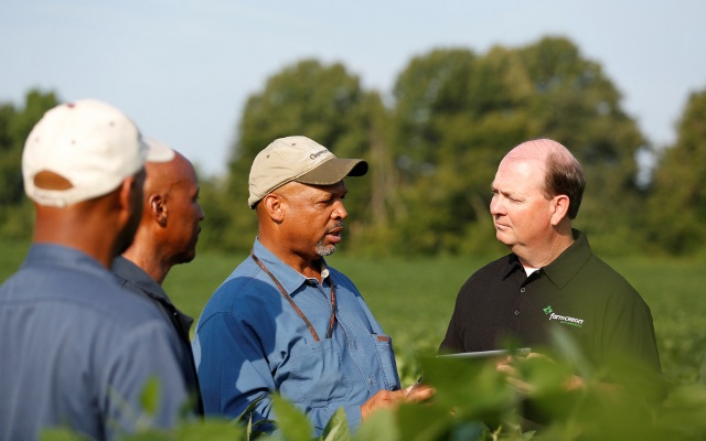 Team member talking to customers in a soybean field.
