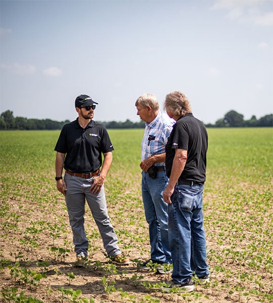 Farm Credit Mid-America Crop Insurance officer talks to customers in soybean field.